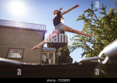 Mädchen springen auf Trampolin im Garten Stockfoto