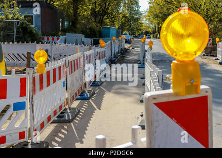 Rote und weiße Barrikaden mit Kontrolllampen auf einer Straße in einem Wohngebiet. Stockfoto