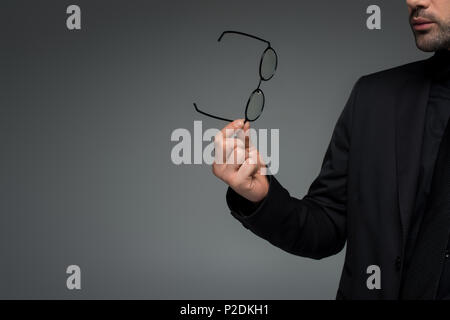 Teilweise mit Blick auf die stilvolle Mann hält Gläser isoliert auf Grau Stockfoto