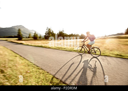 Junge Frau reiten ihr Fahrrad an einem sonnigen Tag, Tannheimer Tal, Tirol, Österreich Stockfoto