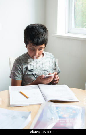 Schüler -10-11 Jahre alt mit Smartphones zu Hausaufgaben, Surrey, Großbritannien