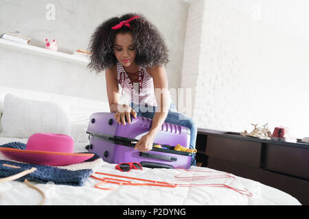 African American Girl Vorbereitung Gepäck für Urlaub und Reisen Stockfoto