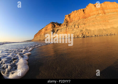 Surfen Sie wäscht auf Torrey Pines State Beach mit den Klippen von Torrey Pines State Reserve im Hintergrund. San Diego, Kalifornien. Stockfoto