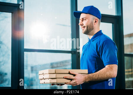 Lächelnd Kurier Pizza, die in den Feldern Stockfoto