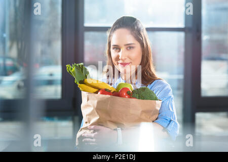 Lächelnde Frau mit Papiertüte mit frischem Obst und Gemüse Stockfoto