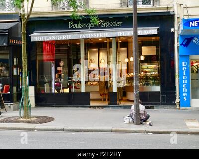 Obdachlosen Mann sitzt auf dem Bürgersteig außerhalb einer Bäckerei, während Frau gut gekleidete Frau Geschäfte im Inneren, Paris, Frankreich Stockfoto