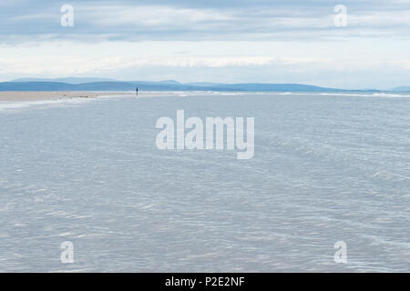 Kleine männliche Figur stehend auf leeren Strand mit Blick auf Meer, Strand, Bucht, Burghead Findhorn, den Moray Firth, Schottland, Großbritannien Stockfoto
