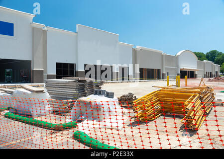 Ein shopping center Baustelle eingezäunt durch orange Verrechnung. Lieferungen sind in der Parkplatz gestapelt. Stockfoto