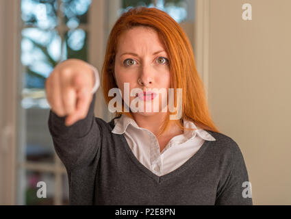 Rothaarige Frau zeigt mit dem Finger auf die Kamera und an Sie, Hand unterzeichnen, positiv und zuversichtlich Geste von vorne Stockfoto