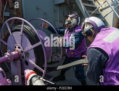 160910-N-GP 524-229 arabischen Golf (Sept. 10, 2016) Gas Turbine System Technician (mechanischen) 3. Klasse Rudolph McKenzie, Mitte, und Gas Turbine System Technician (mechanisch) Feuerwehrmann Mario Orellana Haspel - in einem kraftstoffschlauch nach Hubschrauber tanken Operationen an Bord der geführte Anti-raketen-Zerstörer USS Stout (DDG55). Stout, eingesetzt als Teil der Eisenhower Carrier Strike Group, unterstützt Maritime Security Operations und Theater Sicherheit Zusammenarbeit in den USA 5 Flotte Bereich der Operationen. (U.S. Marine Foto von Mass Communication Specialist 3. Klasse Bill Dodge) Stockfoto