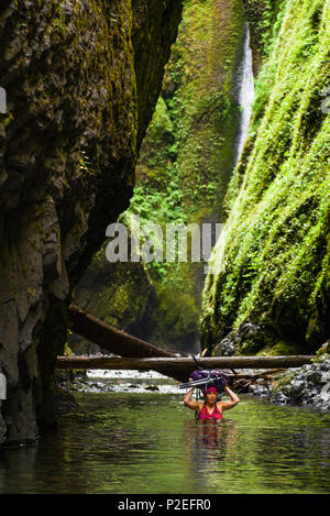 Eine Frau trägt ihr Gang durch die tiefe Stelle in der River Trail zu senken Oneonta fällt, eine der besten Sommer Wanderungen in Oregon.