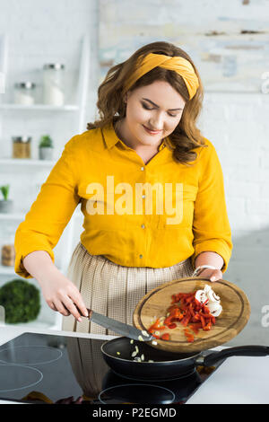 Schöne Frau Gemüse auf die Pfanne in der Küche Stockfoto