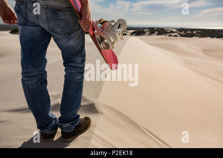 Mann mit Sandboard stehend in der Wüste Stockfoto