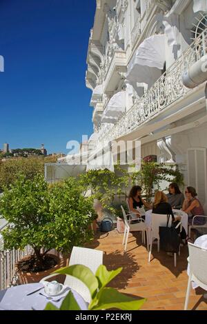 Frankreich, Alpes Maritimes, Cannes, Frauen sitzen auf der Terrasse des herrlichen, das älteste Hotel von Cannes, mit der olf Stadtteil Suquet im Hintergrund Stockfoto