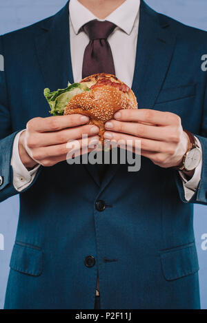 7/8 Schuß von Geschäftsmann in Anzug holding Burger Stockfoto