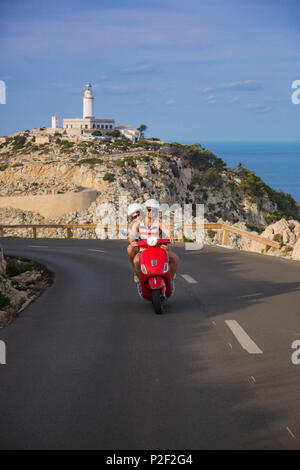 Junges Paar, einem roten Vespa Roller auf der Küstenstraße entlang der Cap de Formentor Halbinsel mit Faro de Formentor Leuchtturm Stockfoto