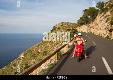 Junges Paar, einem roten Vespa Roller auf der Küstenstraße entlang der Halbinsel Cap de Formentor, Palma, Mallorca, Balearen Insel Stockfoto