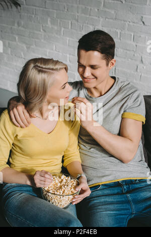 Freund Fütterung Freundin mit Popcorn auf dem Sofa Stockfoto