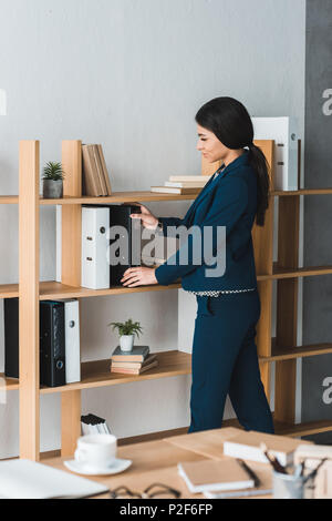 Geschäftsfrau stapeln Ordner im Regal in modernen Büro Stockfoto