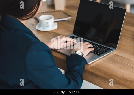 Ansicht der Rückseite des geschäftsfrau Tippen auf Laptop von Tabelle im Büro Stockfoto