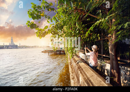 Frau Tourist, der ein Bild von Wat Arun mit Ihrem Telefon bei Sonnenuntergang in Bangkok, Thailand Stockfoto