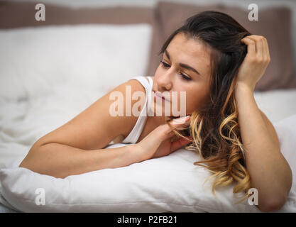 Schöne junge Mädchen mit langen Haaren liegen auf einem weißen Bett, Foto closeup Stockfoto