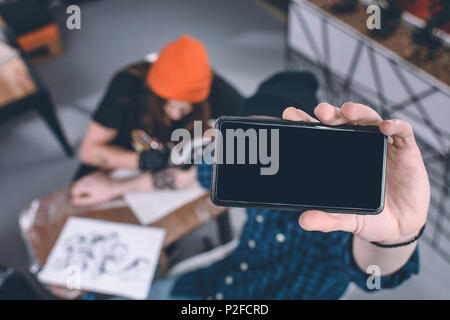 Telefon in männlichen Händen vor der Tätowierung Prozess im Studio Stockfoto