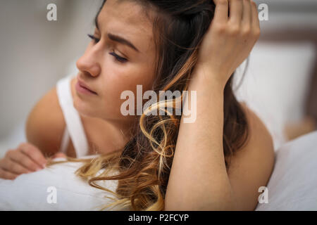 Schöne junge Mädchen mit langen Haaren liegen auf einem weißen Bett, Foto closeup Stockfoto