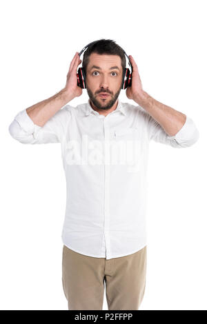 Halbe Länge geschossen von einem jungen Mann hören von Musik in großen Kopfhörer mit überraschten Blick auf seine facera Stockfoto