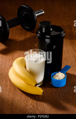 Protein Shake mit hantel und Bananen auf Holz- Oberfläche Stockfoto