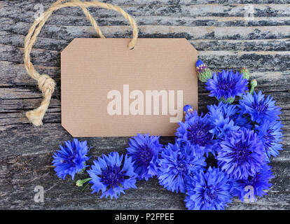 Papier tag mit frischen Kornblumen (Centaurea cyanus) auf Holztisch. Ansicht von oben. Stockfoto
