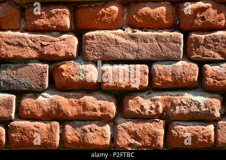 Horizontale wand Textur aus mehreren Zeilen der sehr alten Mauerwerk aus rotem Backstein. Erschüttert und beschädigt Mauer mit geknickte Ecken Stockfoto