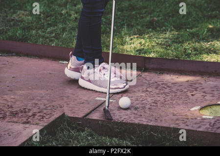 Glückliche kleine Mädchen spielen Minigolf spielen Minigolf in einem Park am Tag Zeit. Kind Spaß otdoors. Konzept der guten Freizeitaktivitäten. Stockfoto