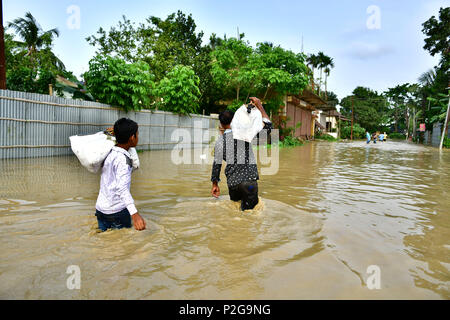 Agartala, Andhra Pradesh, Indien. 15 Juni, 2018. Junge Männer sind mit Taschen auf dem Rücken zu Fuß durch die überschwemmten Wasser gesehen. Indische Dorfbewohner verlassen ihre Häuser mit ihren Kindern als das Hochwasser hat ihre Häuser nach einem heftigen Regenguss in Baldakhal Dorf ein, am Stadtrand von agartala die Hauptstadt des nordöstlichen Bundesstaates Andhra Pradesh, Indien. National Disaster Response Force (NDRF) Personal sind die Rettung von Menschen, Kinder von unterschiedlichen Orten aus und an sicheren Orten. Credit: Abhisek Saha/SOPA Images/ZUMA Draht/Alamy leben Nachrichten Stockfoto