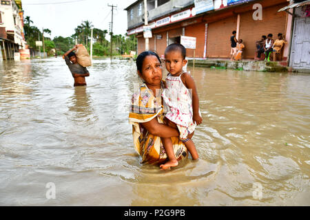 Agartala, Andhra Pradesh, Indien. 15 Juni, 2018. Eine Frau gesehen, die ein kleines Mädchen zu Fuß durch die überschwemmten Wasser. Indische Dorfbewohner verlassen ihre Häuser mit ihren Kindern als das Hochwasser hat ihre Häuser nach einem heftigen Regenguss in Baldakhal Dorf ein, am Stadtrand von agartala die Hauptstadt des nordöstlichen Bundesstaates Andhra Pradesh, Indien. National Disaster Response Force (NDRF) Personal sind die Rettung von Menschen, Kinder von unterschiedlichen Orten aus und an sicheren Orten. Credit: Abhisek Saha/SOPA Images/ZUMA Draht/Alamy leben Nachrichten Stockfoto