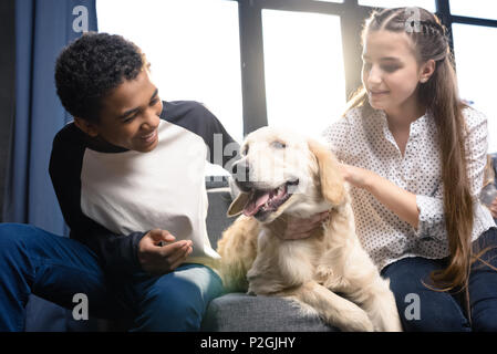 Happy teenage Paar Spaß mit Golden Retriever Hund drinnen, jugendliche Spaß Konzept Stockfoto