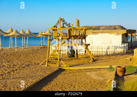 Alten, verlassenen Holz- Kinderspielplätze auf leeren Küste vor dem Hintergrund einer goldgelben Sand und blauer Himmel. Geworfen, unnötige Dinge. Vacatio Stockfoto