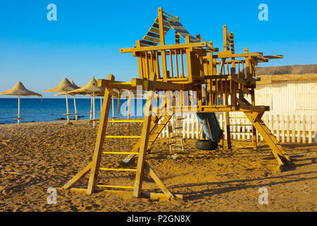 Alten, verlassenen Holz- Kinderspielplätze auf leeren Küste vor dem Hintergrund einer goldgelben Sand und blauer Himmel. Geworfen, unnötige Dinge. Vacatio Stockfoto