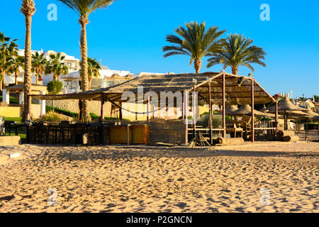 Alten, verlassenen Holz- Kinderspielplätze auf leeren Küste vor dem Hintergrund einer goldgelben Sand und blauer Himmel. Geworfen, unnötige Dinge. Vacatio Stockfoto