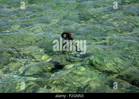 Der alte rostige Kette ist an der Küste im klaren Wasser vor dem Hintergrund der gelben Sand geworfen. Stockfoto