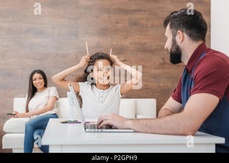 Lächelnd African American Girl, Hörner von Bleistifte während Vater sah sie an Stockfoto