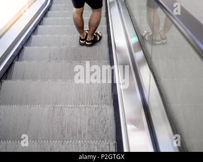 Der Mann in Schwarz Kurz und Sandale auf Rolltreppe Stockfoto