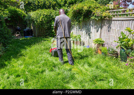 Ein schwarzer Mann langes Gras mähen im Hinterhof Garten Rasen zu Hause Stockfoto