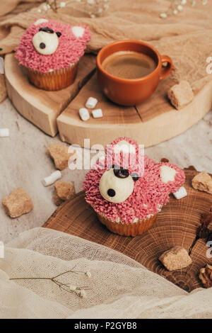Nahaufnahme der süßen Muffins in der Form von Bären und Tasse Kaffee auf Tisch Stockfoto