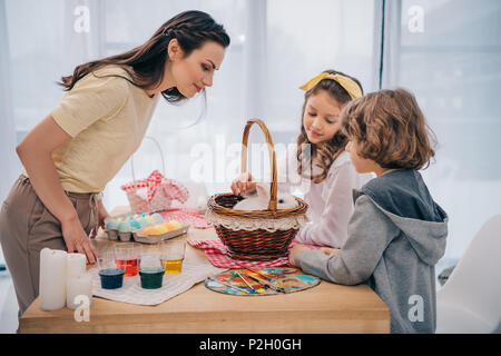 Kinder und Mutter spielt mit Ostern Kaninchen zu Hause auf dem Tisch Stockfoto