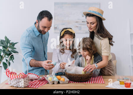 Junge Familie Vorbereitung auf Ostern Urlaub mit Häschen im Korb sitzen am Tisch Stockfoto