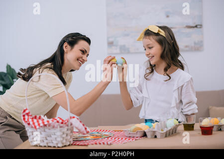 Glückliche junge Mutter und Tochter tun Ei tippen auf Ostern Stockfoto