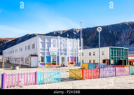 Moderne grönländisch Kindergarten mit Spielplatz und bunten Zaun in der Tundra mit felsigen Hügeln im Hintergrund, Kangerlussuaq, Grönland Stockfoto