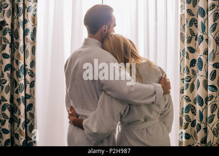 Rückansicht des Reifes Paar in der Liebe tragen Bademäntel und Umarmen im Hotel Zimmer Stockfoto