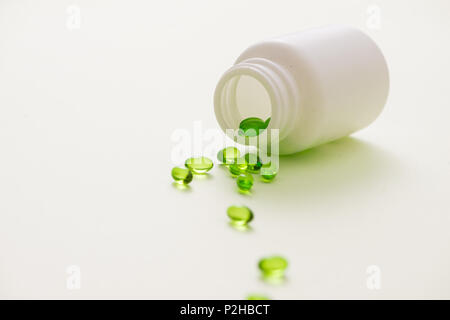 Grüne kapseln in einer Flasche auf weißem Hintergrund Stockfoto